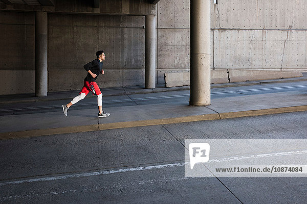 Young male runner running up city underpass