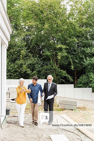 Vorderansicht in voller Länge des Paares das mit dem Architekten über die Sanierung von Wohnraum diskutiert