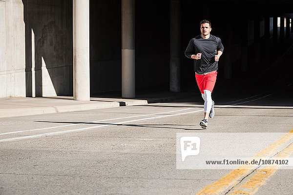 Young male runner running from city underpass