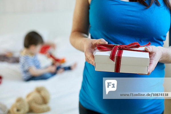 Schrägansicht einer schwangeren Frau mit Geschenkbox