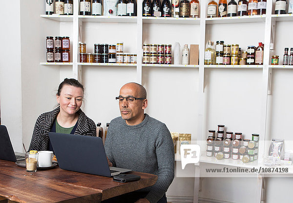Couple sitting at cafe table browsing laptop