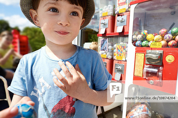 Glücklicher Junge neben Kaugummiautomat
