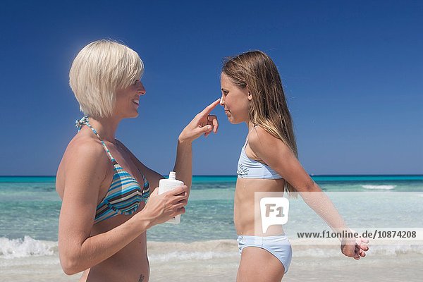 Junge Frau cremt die Nase von Töchtern am Strand mit Sonnencreme ein  Mallorca  Spanien