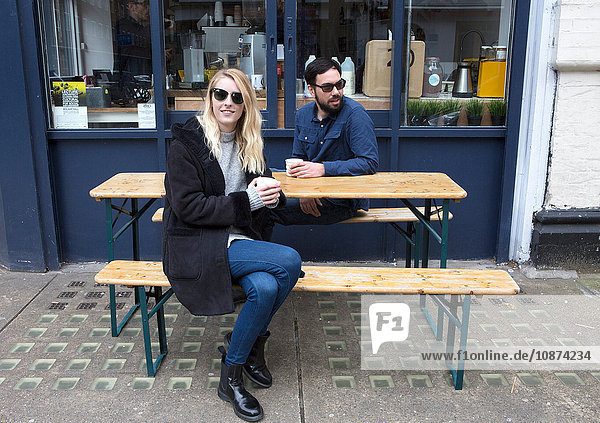 Couple sitting watching from sidewalk cafe table