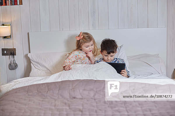 Kinder mit digitalem Tablett im Bett
