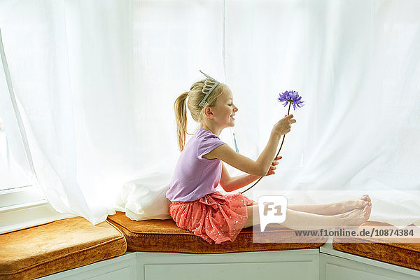 Mädchen mit Diadem  das eine Blume am Erkerfenster hält