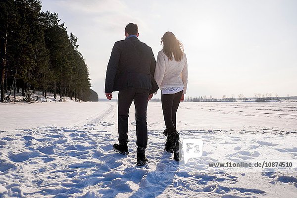 Young couple walking on snow-covered field
