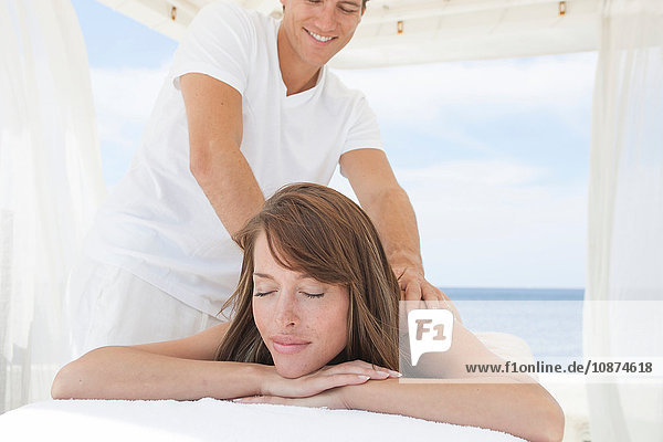 Masseur giving young woman a shoulder massage at beach resort  Majorca  Spain