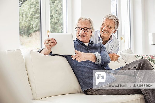 Two men at home looking at digital tablet