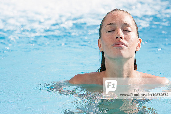 Porträt einer schönen jungen Frau mit geschlossenen Augen im Schwimmbad des Thermalbads