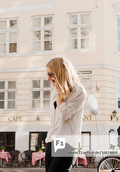 Frau benutzt Mobiltelefon gegenüber Café  Kopenhagen  Dänemark