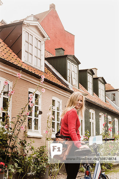 Frau schiebt Fahrrad an Häusern vorbei  Aarhus  Dänemark