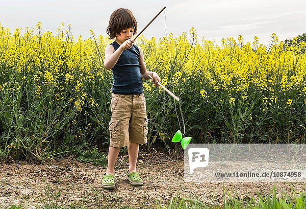 Junge in gelbem Blumenfeld spielt mit Diabolo