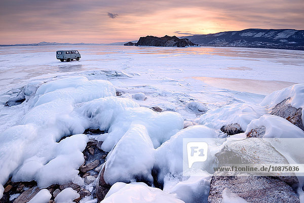 Blick auf ein Geländefahrzeug für Touristen und die Insel Oltrek bei Sonnenuntergang  Baikalsee  Insel Olchon  Sibirien  Russland