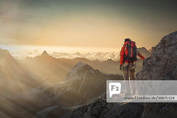 Climber watching a mountain range at sunset  Alps  Canton Wallis  Switzerland