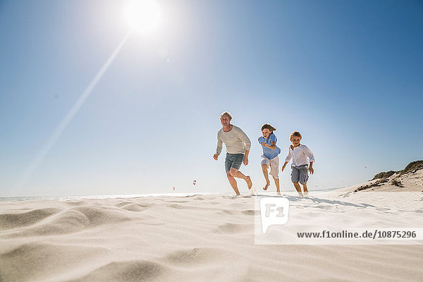Father and sons running on beach