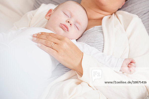 Mother lying on bed  holding baby boy  mid section
