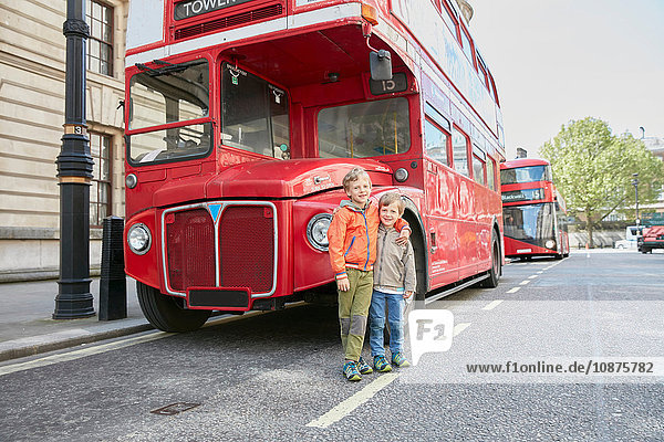 Boys in front of red double decker bus