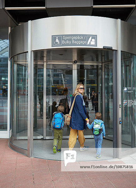 Rückansicht von Mutter und Söhnen beim Betreten des Flughafenterminals