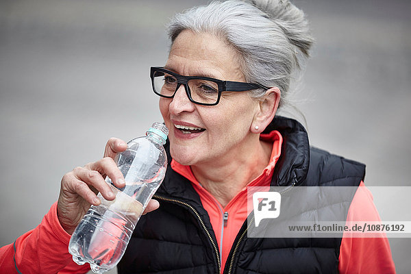 Ausbildung einer reifen Frau in der Stadt  Trinken von Flaschenwasser