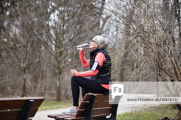 Reife Frau trainiert im Park  trinkt Flaschenwasser