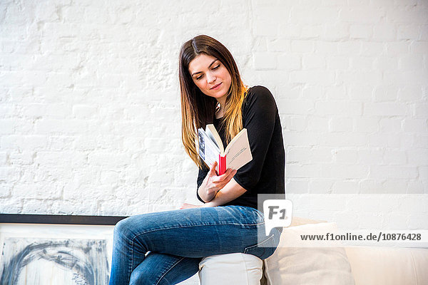 Hübsche junge Frau in stilvoller Wohnung liest Buch