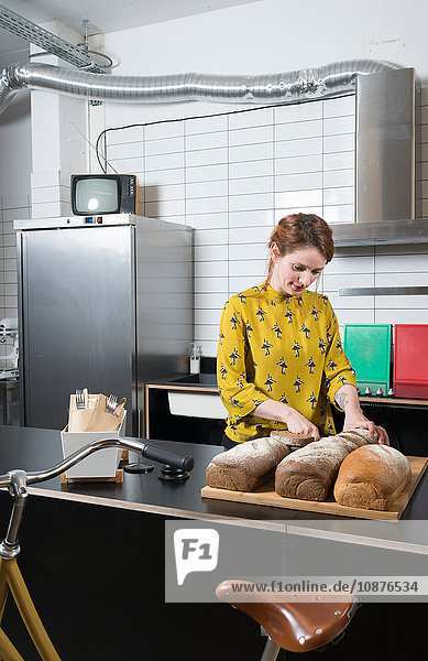 Kellnerin schneidet Brot an der Theke eines Hipster-Rad-Reparatur-Cafés