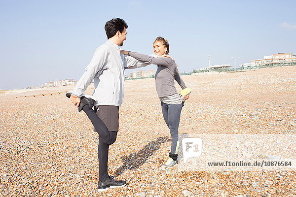 Mann und Frau trainieren  auf einem Bein stehend am Strand von Brighton