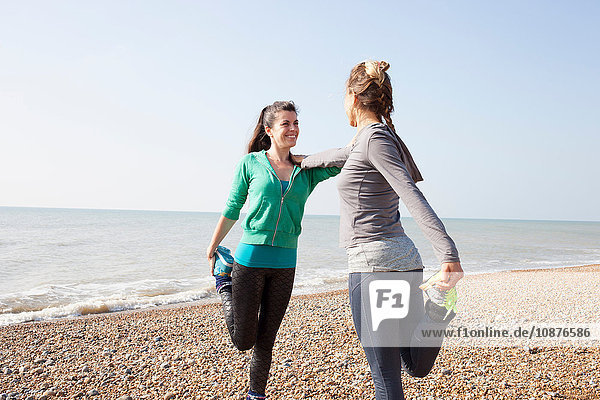 Zwei Frauen trainieren  auf einem Bein stehend am Strand von Brighton