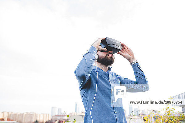 Junger männlicher Designer testet Virtual-Reality-Headset auf Büro-Dachterrasse