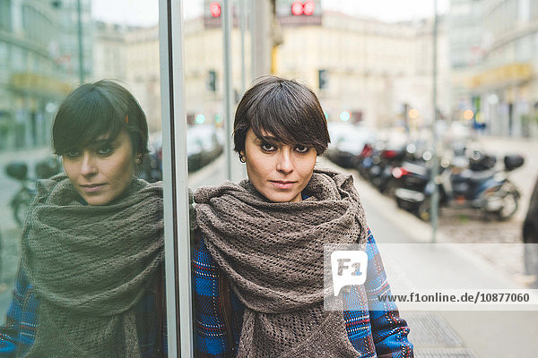 Portrait of young woman leaning against window  outdoors