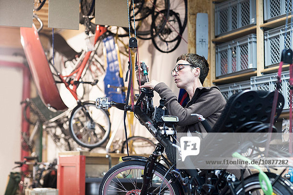 Woman in bicycle workshop repairing recumbent bicycle