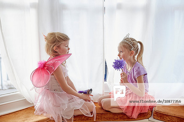 Zwei junge Mädchen in Kostümen  von Angesicht zu Angesicht sitzend