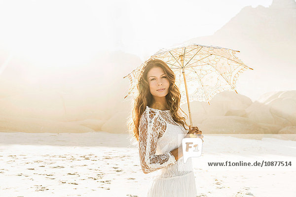 Porträt einer schönen Frau mit Sonnenschirm am sonnenbeschienenen Strand  Kapstadt  Südafrika