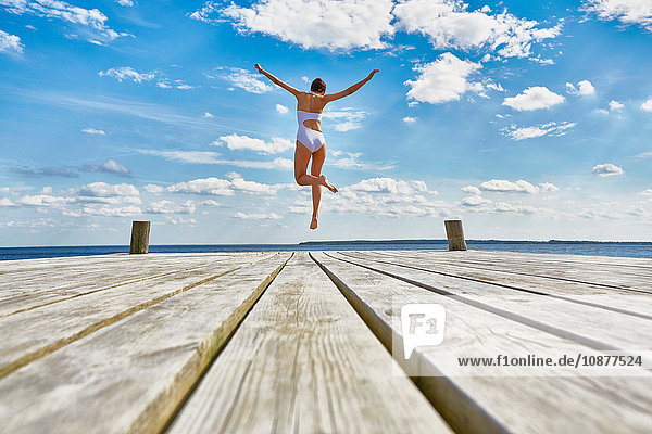 Junge Frau tanzt auf einem Holzsteg  mittlere Luft  Rückansicht