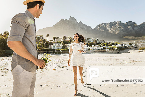 Woman running to boyfriend with flower bouquet on beach  Cape Town  South Africa