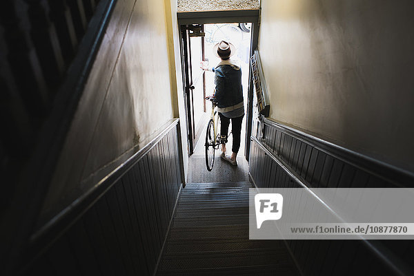 Junger Mann unten an der Treppe  Verlassen des Gebäudes mit Fahrrad  erhöhte Ansicht