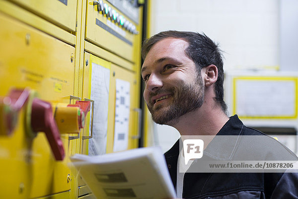 Man holding instruction manual by control panel smiling