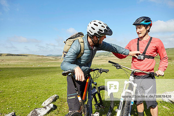 Radfahrer am Berghang befestigen Aktionskamera am Freund