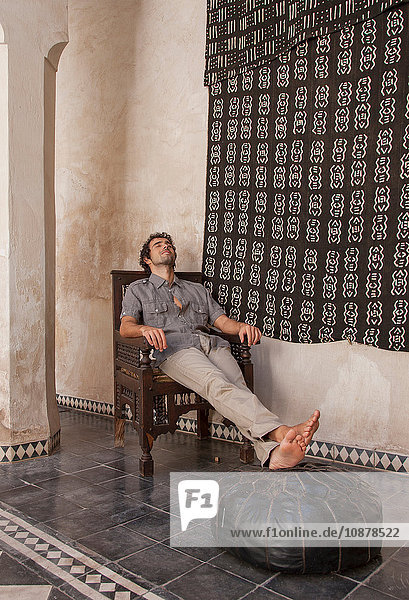 Mann sitzt mit erhobenen Füßen auf Puff  Marrakesch  Marokko