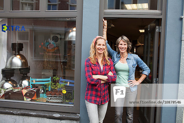 Women standing in shop doorway looking at camera smiling