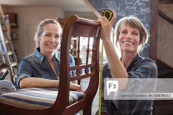 Woman in workshop with chair looking at camera smiling