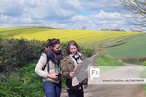 Zwei junge Frauen stehen auf der Landstraße und schauen auf die Karte