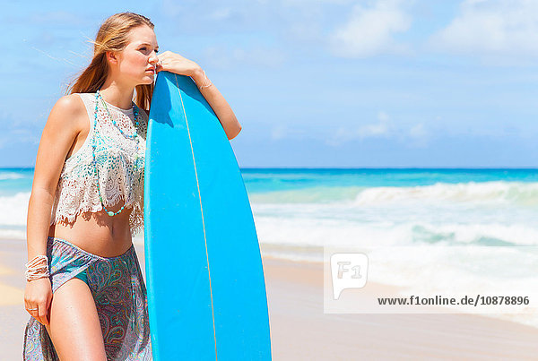 Junge Frau lehnt am Strand gegen ein Surfbrett  Dominikanische Republik  Karibik