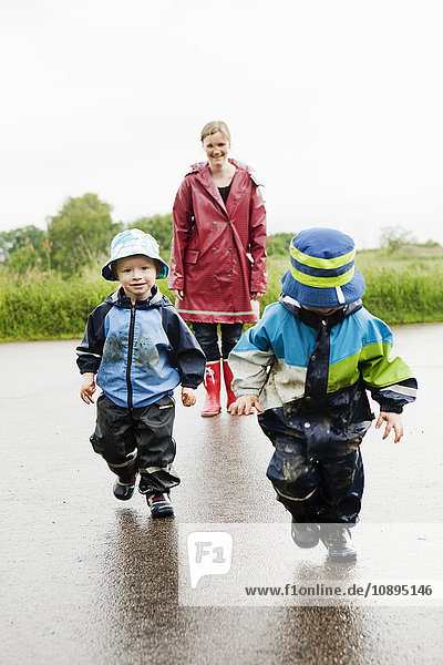 Schweden  Skane  Arild  Mutter und Töchter (2-3  4-5) auf nasser Straße unterwegs