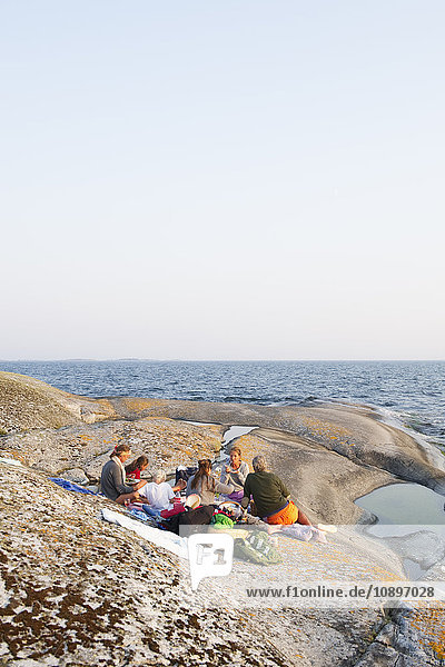 Schweden  Stockholms Archipel  Sodermanland  Haninge  Norsten  Menschen beim Picknick auf Felsen am Meer