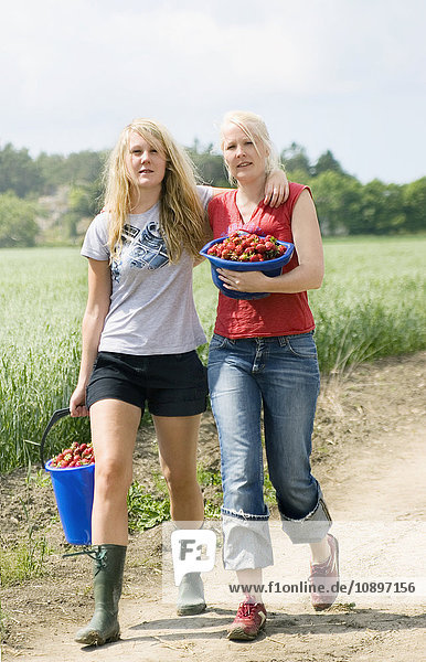 Schweden,  Bohuslan,  Tjorn,  Zwei Frauen,  die mit Eimern voller Erdbeeren gehen.