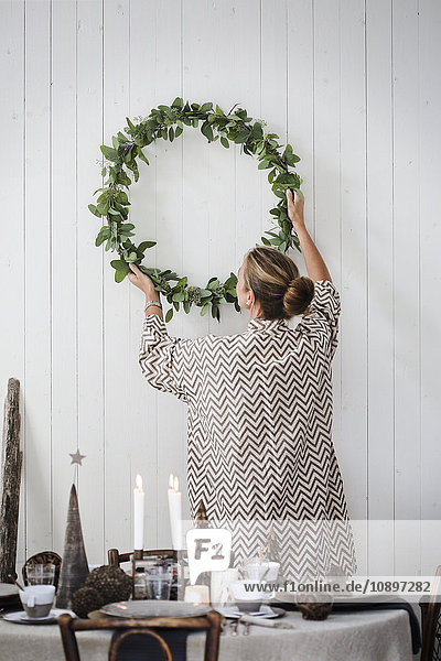 Sweden  Woman hanging Christmas wreath on wall
