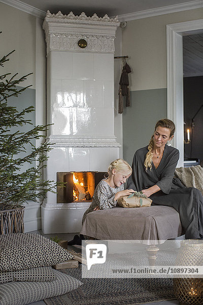 Sweden  Mother and daughter (6-7) sitting by fireplace opening Christmas presents