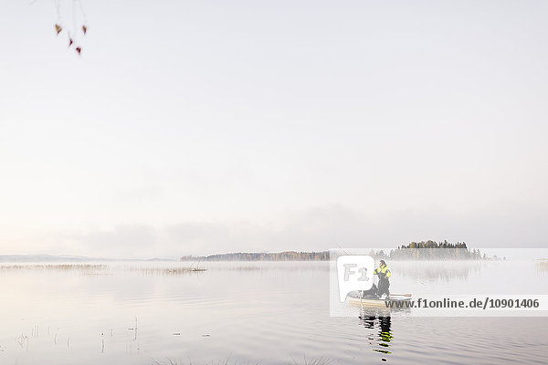 Sweden  Vastmanland  Bergslagen  Torrvarpen  Young men fishing in lake at sunset